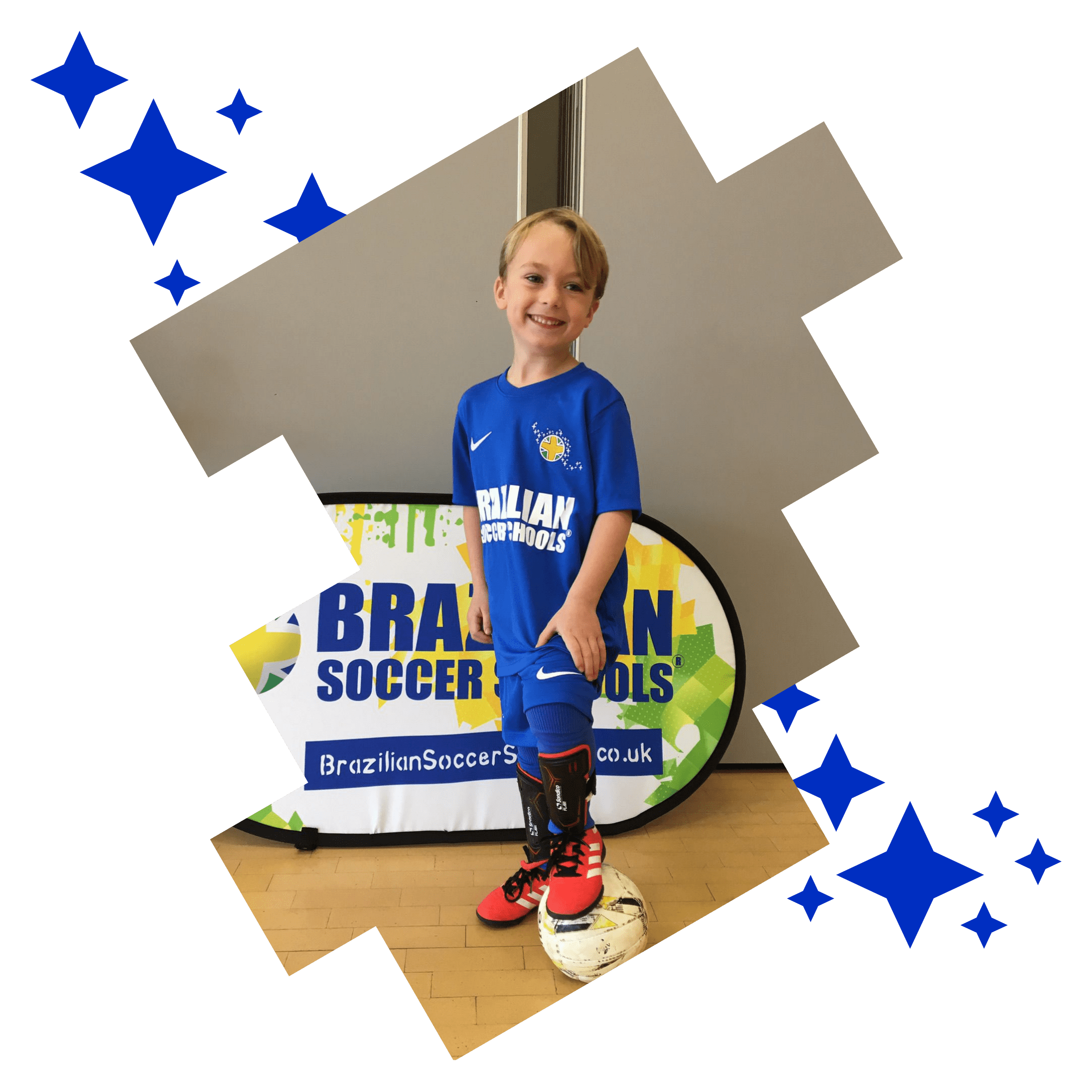 Image shows a Brazilian Soccer Schools student standing infront of the BSS sign and resting one foot on top of the football. 