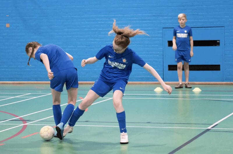 Benefits of football training for 8 year olds. Image shows a BSS class in which students are working on their football skills.