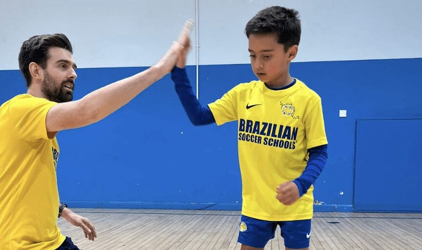 Football coaching near me. Image shows a BSS student high-fiving a football coach.