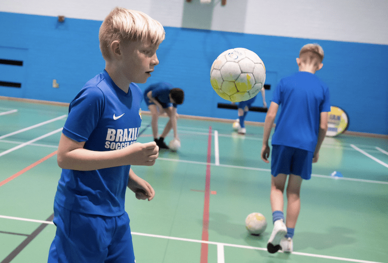 Football club near me. Image shows a boy kicking a football during a Brazilian Soccer Schools training session.