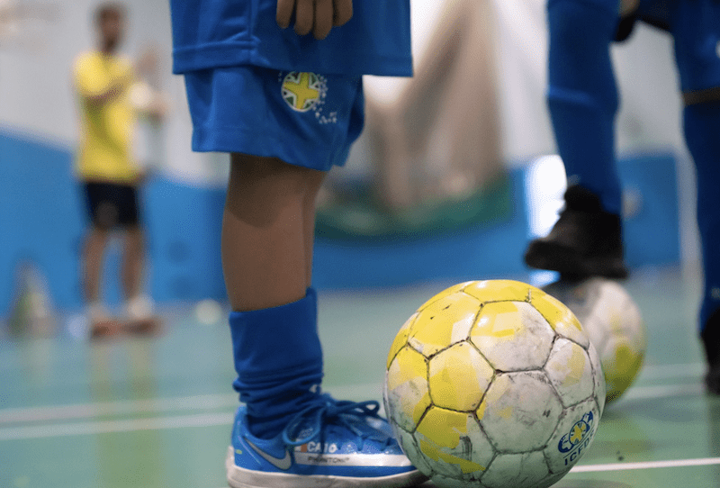 Football training near me. Image shows a Brazilian Soccer Schools football with a small player standing next to it.