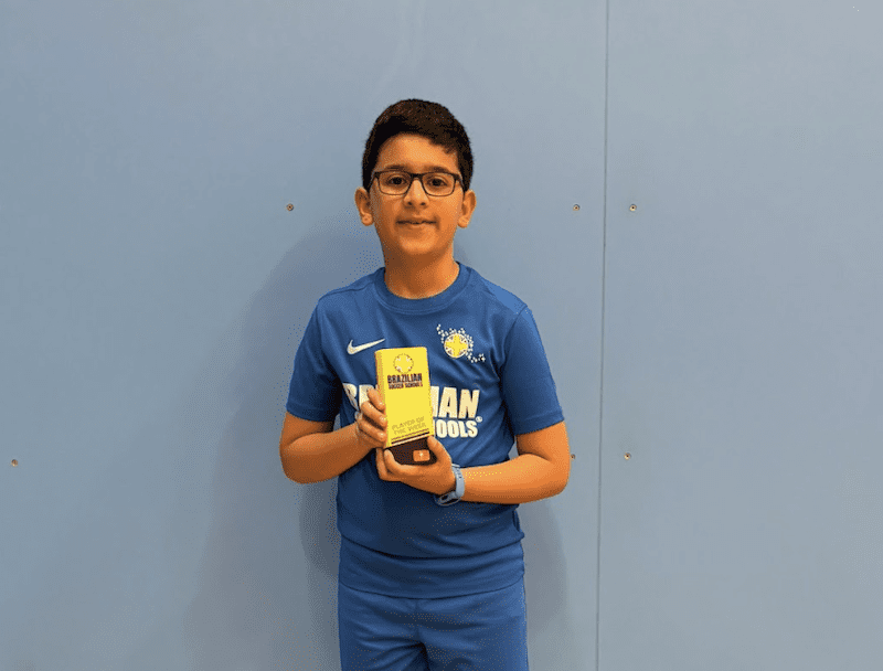 Kids football classes in Leighton Buzzard. Image shows a Brazilian Soccer Schools student dressed in BSS uniform standing with his yellow BSS trophy.