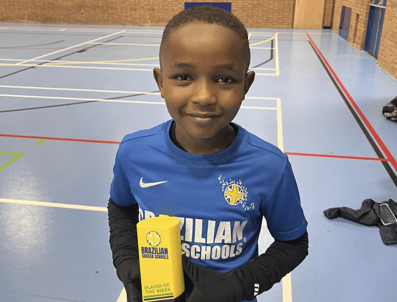 Kids football classes Sunderland. Image shows a Brazilian Soccer Schools student holding a player of the month trophy.