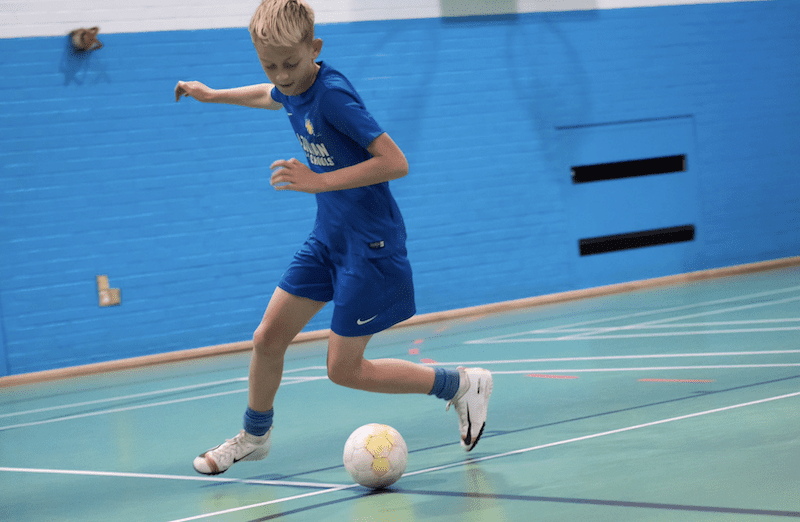 Kids football classes near me. Image shows a boy dribbling a football during a Brazilian Soccer Schools class.