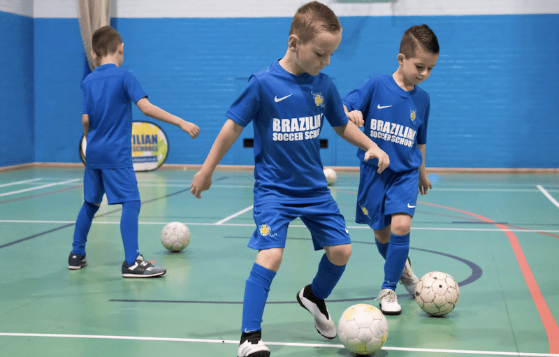 Kids football club Milton Keynes. Image shows 3 boys practicing football drills during a Brazilian Soccer Schools session. 