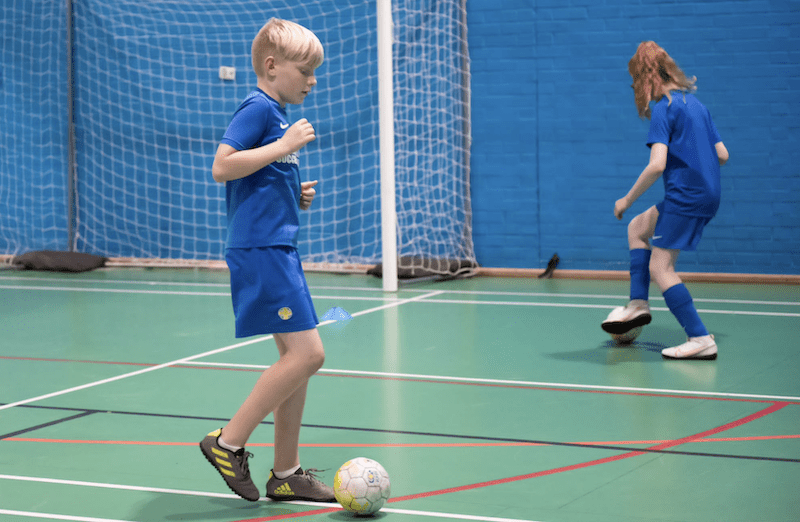 Kids football training Bedford. Image shows two kids dribbling footballs during a Brazilian Soccer Schools session.