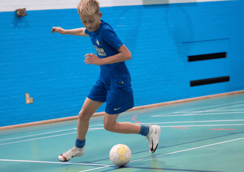 Football training for teenagers. Image shows a teenage boy practicing football skills during a Brazilian Soccer Schools session.
